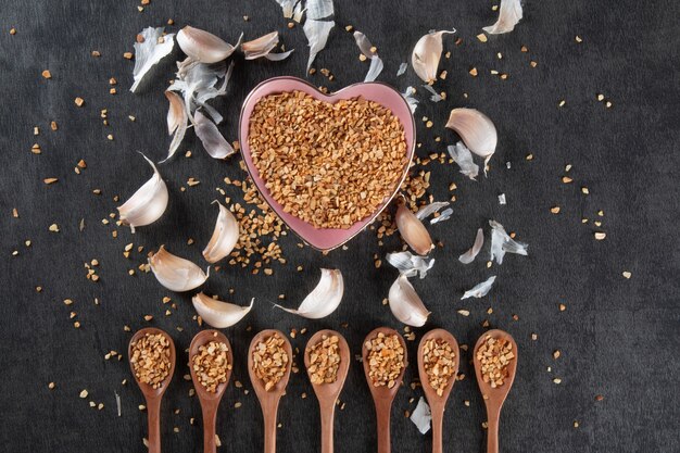 Garlic Cloves and Bulb in Heart Bowl with Dark Background.