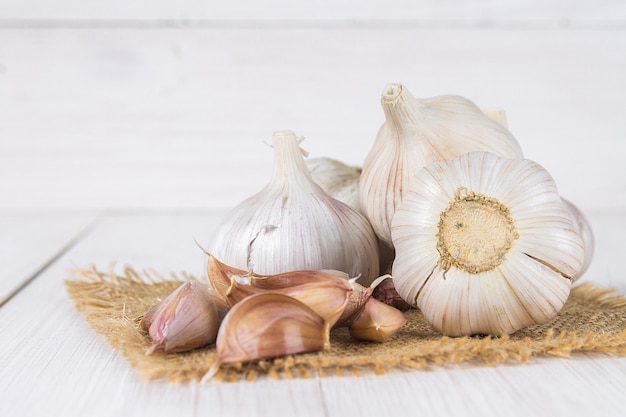 Chiodi di garofano di aglio e lampadina dell'aglio su una tavola di legno bianca