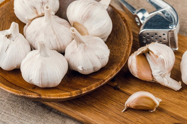 Spicchi d'aglio in piatto di legno su sfondo di tela