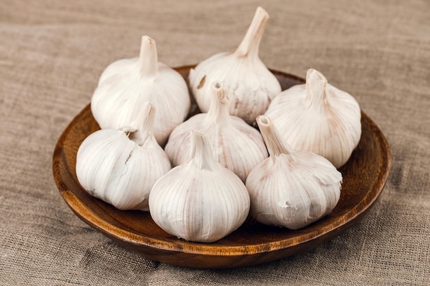 Garlic cloves in wooden plate on burlap background