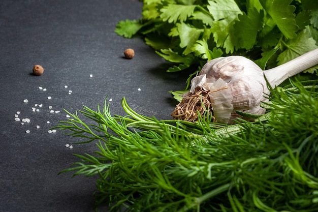 Photo garlic and fresh herbs on a black slate stone organic garlic peppers salt and herbs