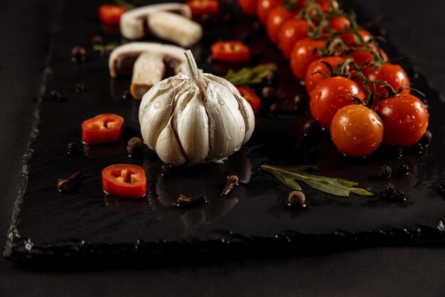 Garlic garlic on a black background with tomatoes and mushrooms