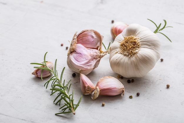 Garlic. Garlic bulbs. Fresh garlic with rosemary and pepper on white concrete board.