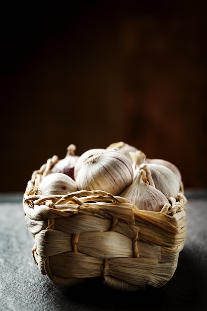 Garlic gloves in a basket on dark grey background