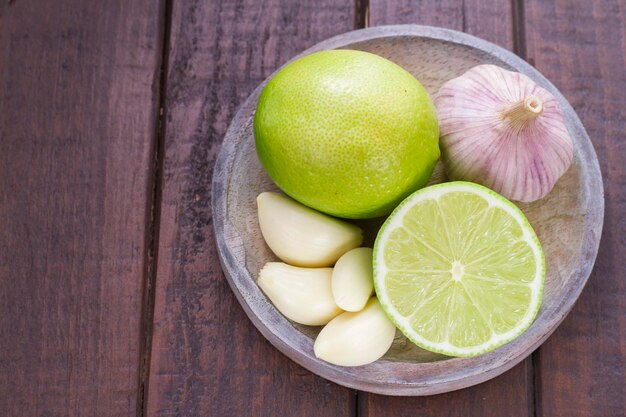 Photo garlic and lemon in bowl on wooden table