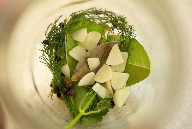 Garlic pepper dill and other ingredients are placed in the bottom of the jar for canning