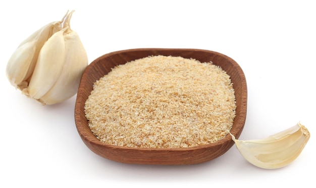 Garlic powder in a bowl with whole over white background