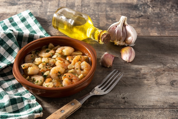 Garlic prawns in crockpot on wooden table