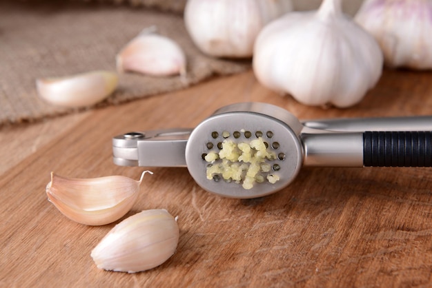 Photo garlic press with garlic on wooden background