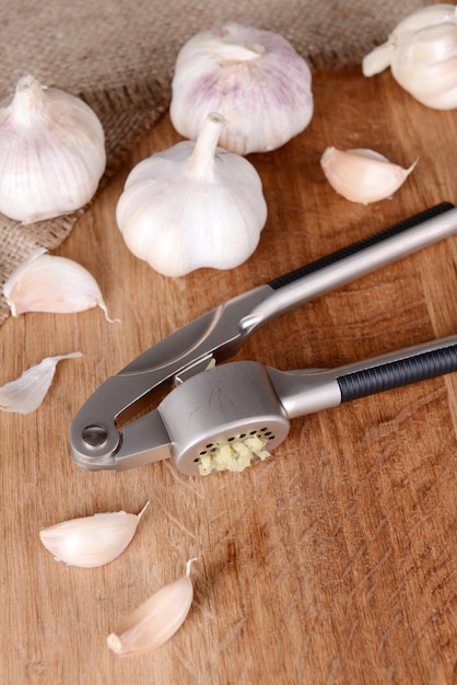 Photo garlic press with garlic on wooden background