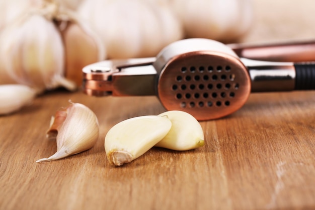 Photo garlic press on wooden background