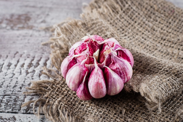 Garlic on rustic napkin on wooden backgrund table. Copy space