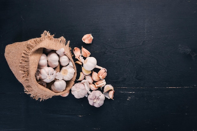 Garlic in a sack of old cloth. Fresh garlic on a wooden background. Top view. Free space for text.