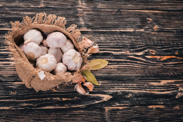 Garlic in a sack of old cloth Fresh garlic on a wooden background Top view Free space for text