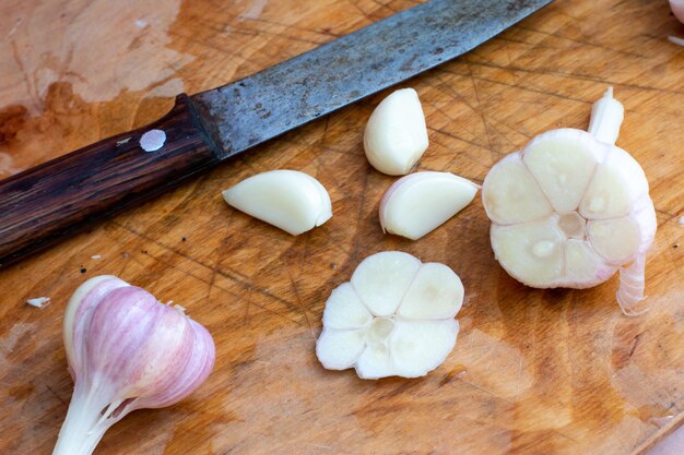 Garlic sliced on wooden background. Concept healthy organic cut garlic - eating superfood on rustic wood kitchen chopping board. Garlic chopped food smell ingredient