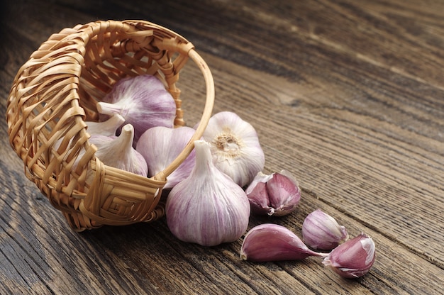 Garlic in a wicker basket and near on wooden table