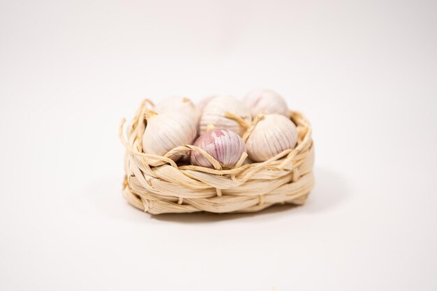 Garlic in a wicker basket on a white background Dried French garlic Red garlic