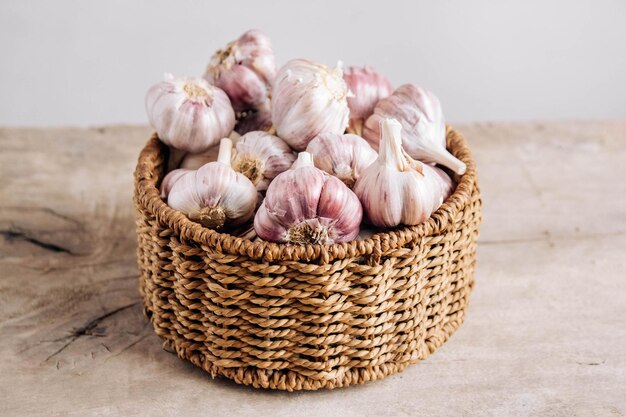 Garlic in a wicker basket on a wooden table background