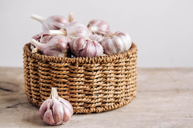 Garlic in a wicker basket on a wooden table background