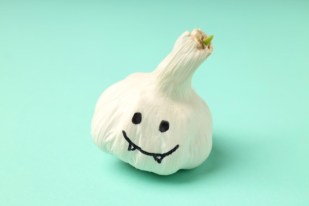 Garlic with eyes and fangs on mint background