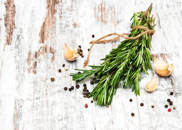 Garlic with rosemary and pepper on a old wooden background