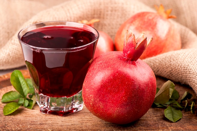 Garnet juice in a glass and pomegranate on wooden boards, on natural fabric