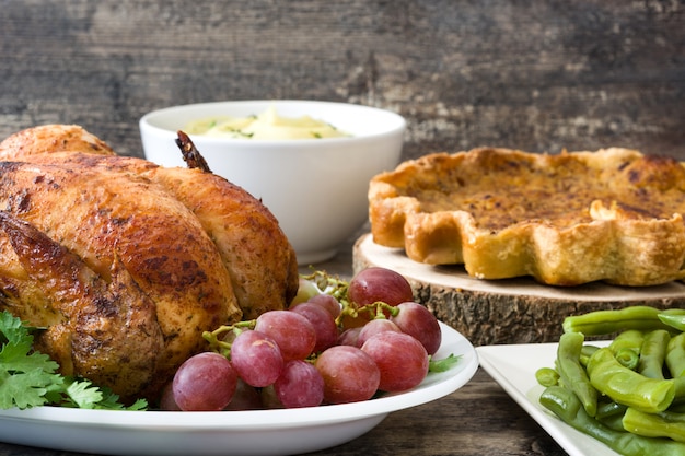 Garnished roasted turkey with grapes and herbs, pumpkin pie and mashed potato 