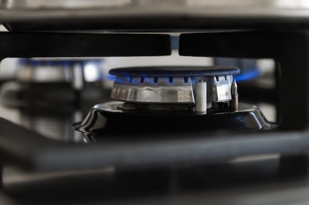 Gas burning from a kitchen gas stove. Blue gas flame on hob. Closeup, selective focus