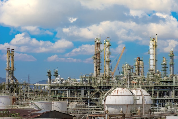 Фото Газовая дистилляционная башня и дымовая труба нефтяного промышленного завода на фоне голубого неба