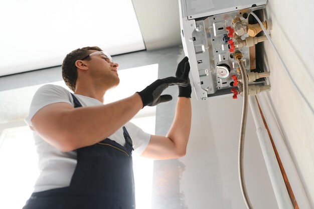 Gas engineer checking and cleaning a boiler during the inspection at home