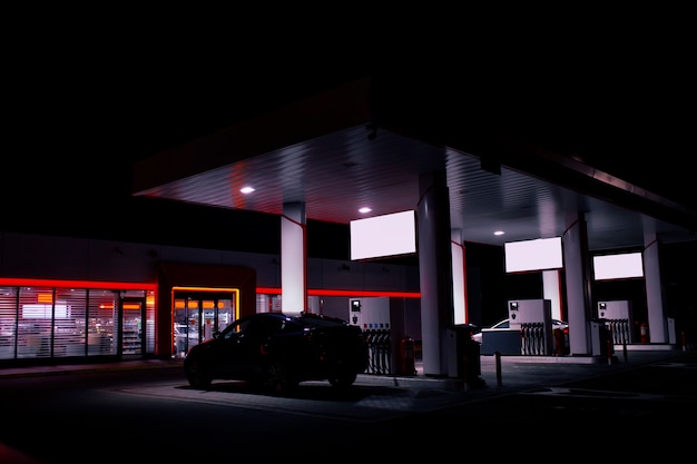 Photo a gas hose is installed in a car at a night gas station with a store bright lights.