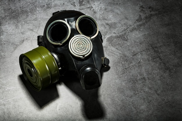 Gas mask on a black stone background with a green filter cartridge. Post-apocalyptic concept.