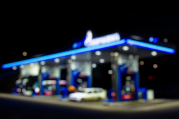 夜のガソリンスタンド。車はガソリンで燃料を供給されています。背景のぼやけた写真。