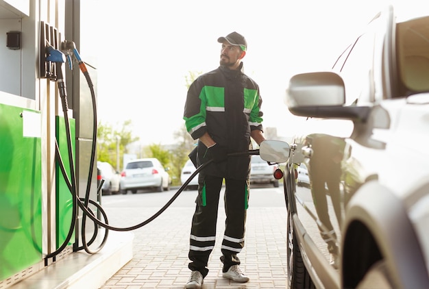 Photo gas station worker looking at pump