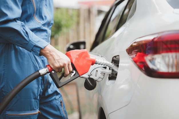 I lavoratori delle stazioni di servizio stanno facendo rifornimento di carburante alle auto, il consumo di carburante di auto a benzina che fluttuano i prezzi del petrolio utilizzando carburanti alternativi per la guida
