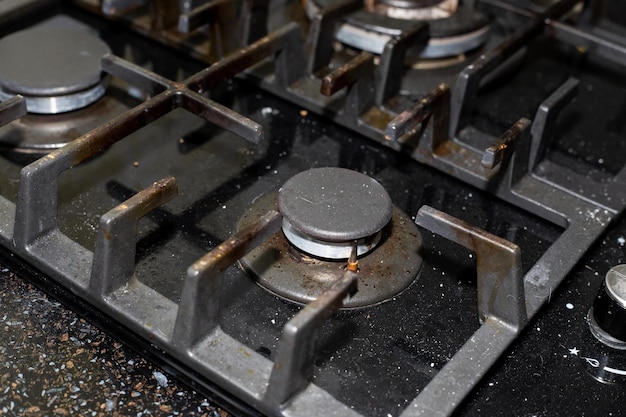 Gas stove with black tempered glass surface with a layer of dust and dirt from cooking