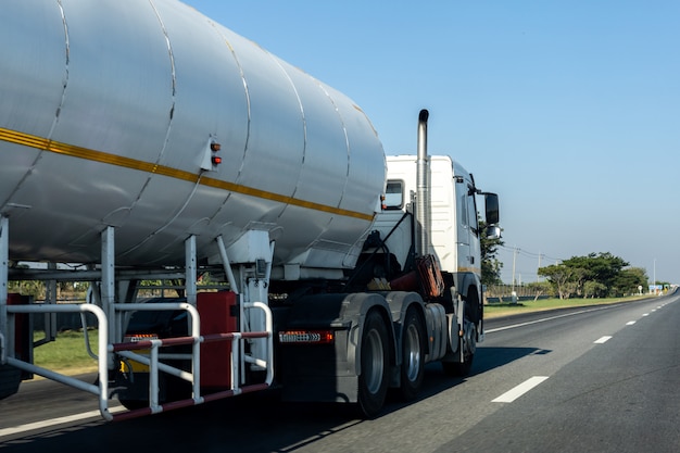 Foto camion del gas sulla strada della strada principale con il contenitore dell'olio del carro armato, trasporto sulla superstrada dell'asfalto con cielo blu