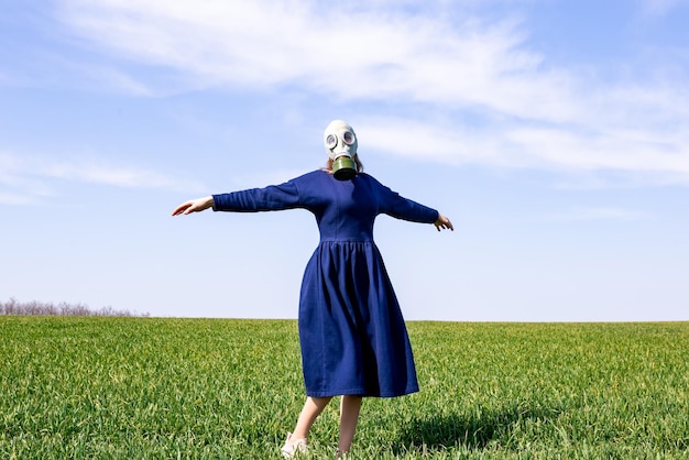 Gasmasker op het gezicht van een jong meisje Een jong meisje in het midden van een groen veld