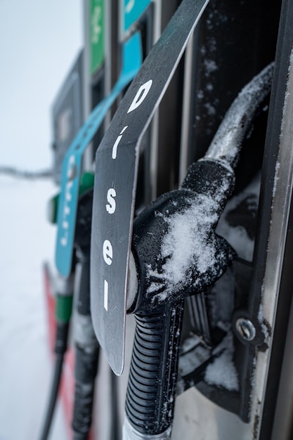 ガソリンまたはディーゼルの給油ホースと銃は、雪に囲まれ、朝の陽光に照らされています