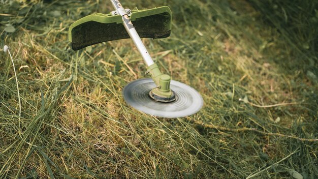 Gasoline trimmer head on green grass. Round trimmer blade.