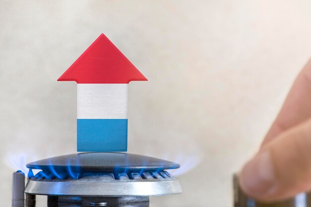 Gasprijs Stijging van de gasprijzen in Luxemburg Een brander met een vlam en een pijl omhoog geschilderd in de kleuren van de Luxemburgse vlag Het concept van stijgende gas- of energieprijzen