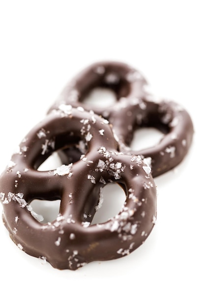 Gastronomische chocolade bedekte pretzel met zeezout op een witte achtergrond.