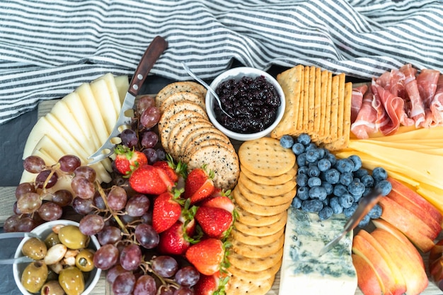 Gastronomische kaas, crackers en fruit op een houten snijplank dienden als aperitief.