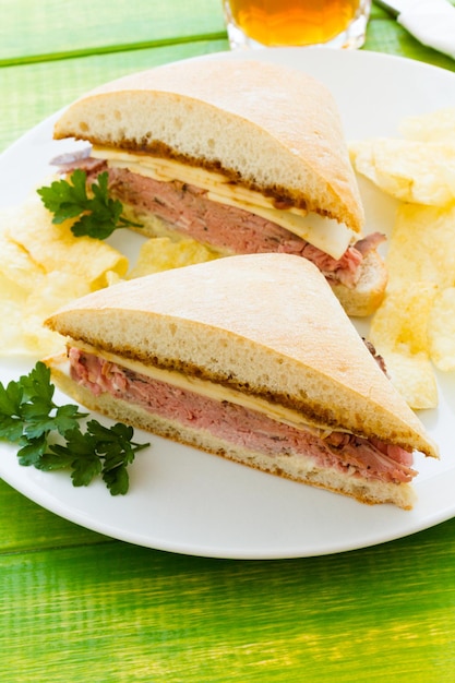 Gastronomische rosbiefsandwich met frietjes aan de zijkant.