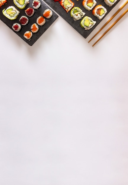 Gastronomische sushi lade op leisteen oppervlak op witte achtergrond met stokjes
