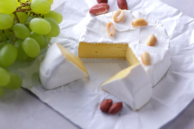 Gastronomische witte brie of camembert kaas met bessen, honing en noten op een witte achtergrond Stilleven van kaas, honing, walnoten en druiven Closeup