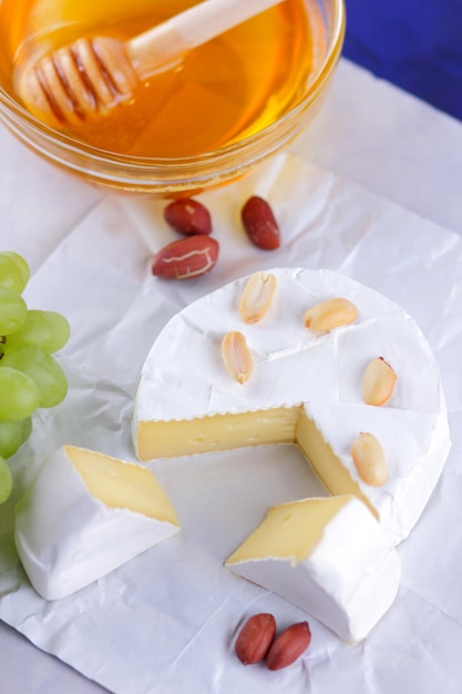 Gastronomische witte brie of camembert kaas met bessen, honing en noten op een witte achtergrond Stilleven van kaas, honing, walnoten en druiven Closeup