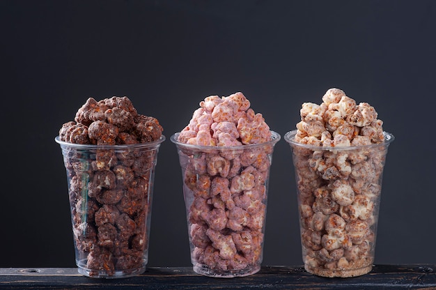 Gastronomische zoete popcorn in plastic beker. gevarieerde smaken, aardbei, chocolade en karamel