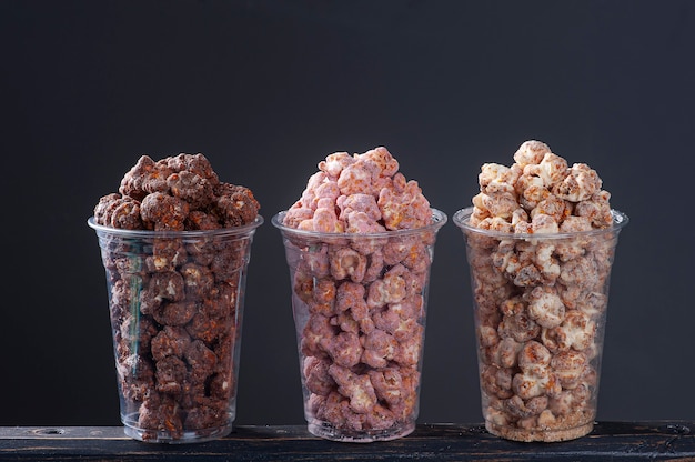 Gastronomische zoete popcorn in plastic beker. Gevarieerde smaken, aardbei, chocolade en karamel