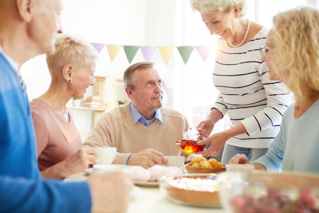 Gastvrije dame die thee schenkt aan vrienden